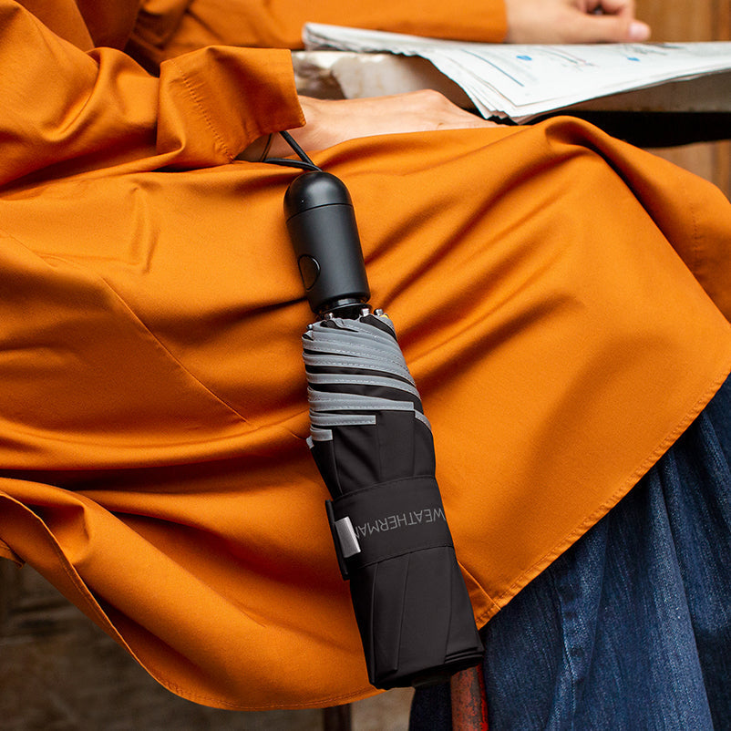 Person holding Weatherman Travel Umbrella in black.