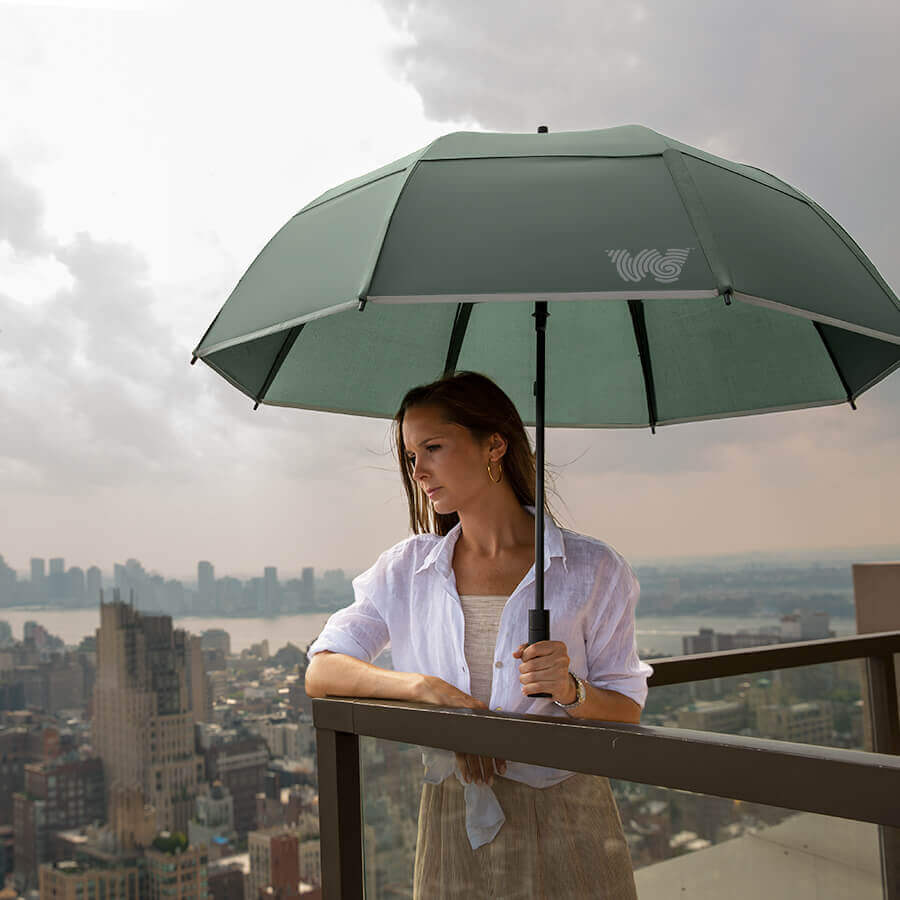 Woman holding opened Weatherman Stick Umbrella in sage green.