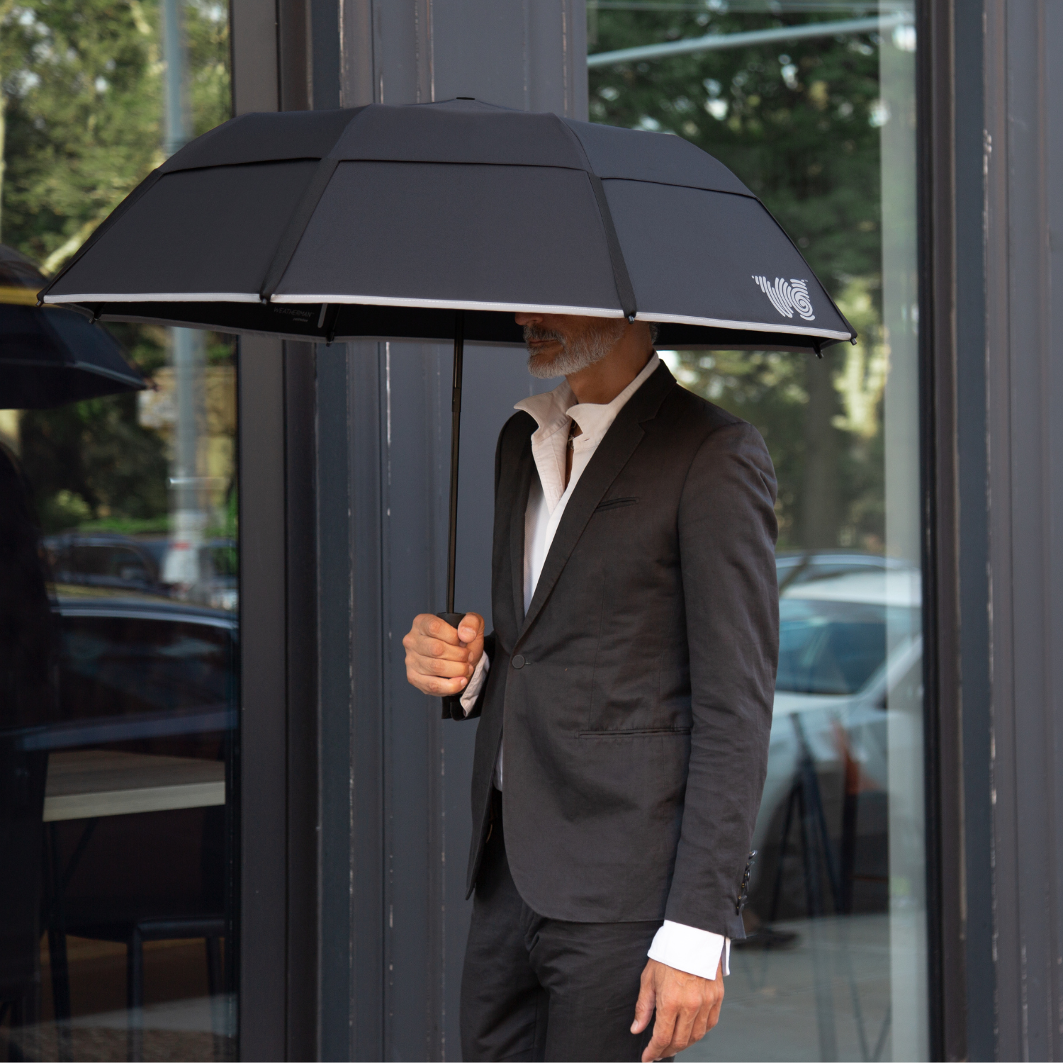 Man walking with opened Weatherman Collapsible Umbrella in black.